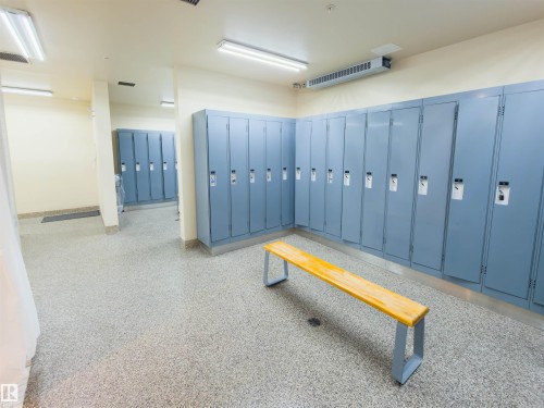 Locker room featuring extensive built-in storage with individual units, durable speckled flooring, and integrated overhead fluorescent lighting - 135 7825 71 Street, Edmonton, AB - Indoor Photo Showing Other Room