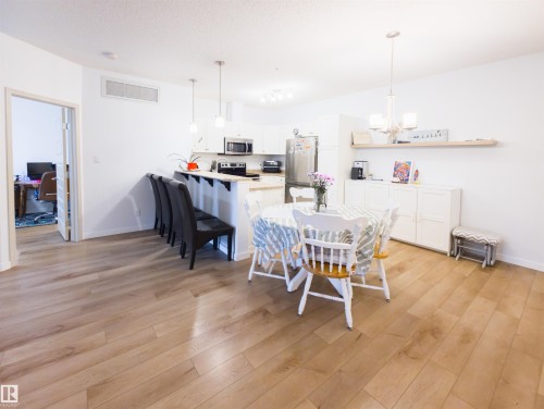 Open-concept living area featuring light wood-finish flooring, white walls, and a recessed ceiling vent - 135 7825 71 Street, Edmonton, AB - Indoor Photo Showing Dining Room