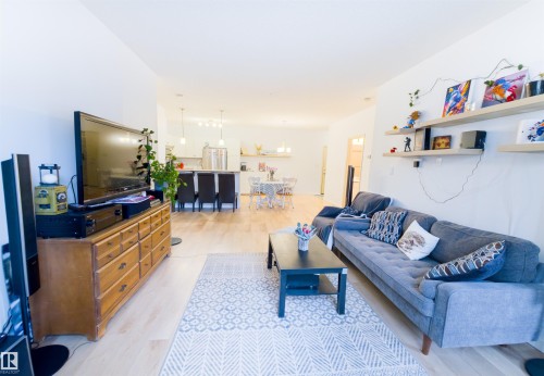 Bright living space featuring wood-finish flooring, white walls, and built-in floating shelves - 135 7825 71 Street, Edmonton, AB - Indoor Photo Showing Living Room