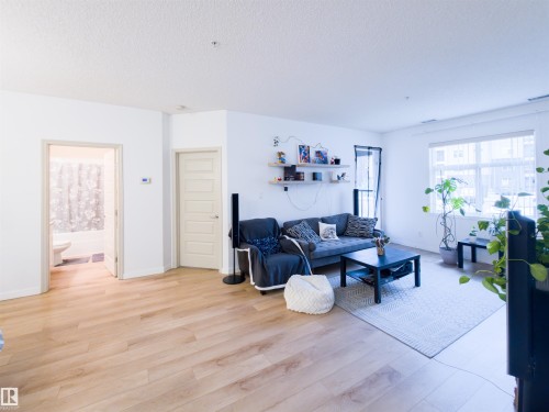 Living area featuring wide plank wood-finish flooring, white walls, and a large window - 135 7825 71 Street, Edmonton, AB - Indoor Photo Showing Living Room