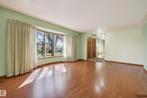 Spacious interior featuring wood-finish flooring and a curved bay window - 12016 51 Street, Edmonton, AB - Indoor