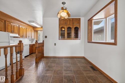 Tiled flooring throughout a dining area featuring a bay window, an overhead chandelier, and built-in wood cabinetry - 12016 51 Street, Edmonton, AB - Indoor