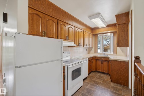 Kitchen featuring wood cabinetry, white appliances, a white tile backsplash, a window above the sink, and tiled flooring - 12016 51 Street, Edmonton, AB - Indoor Photo Showing Kitchen