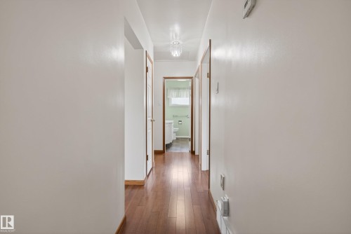 Hallway with wood-finish flooring, white walls, and wood trim around doorways - 12016 51 Street, Edmonton, AB - Indoor Photo Showing Other Room