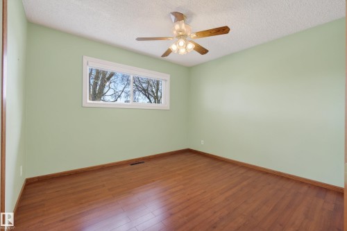 Interior room featuring wood-finish flooring, light green walls, a white-framed window, and a ceiling fan with integrated lighting - 12016 51 Street, Edmonton, AB - Indoor Photo Showing Other Room
