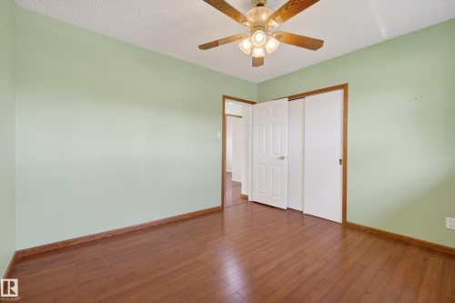 Interior room featuring wood-finish flooring, light green walls, and a ceiling fan with integrated lighting - 12016 51 Street, Edmonton, AB - Indoor Photo Showing Other Room