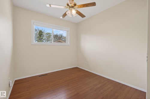 Room featuring wood-finish flooring, a ceiling fan with light fixture, and a window with white trim - 12016 51 Street, Edmonton, AB - Indoor Photo Showing Other Room