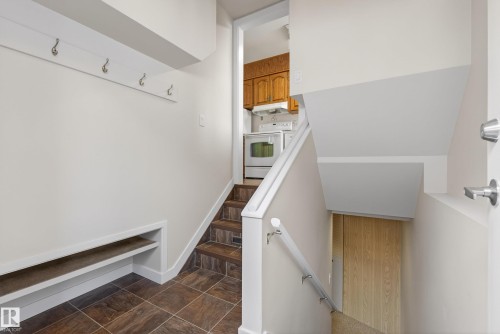 Entry area featuring square tile flooring, a wall-mounted coat rack, and an integrated shoe shelf - 12016 51 Street, Edmonton, AB - Indoor