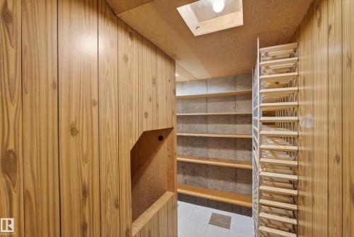 Storage room featuring wood-finish paneling, built-in shelving, concrete block wall, recessed lighting, and tile flooring - 12016 51 Street, Edmonton, AB - Indoor Photo Showing Other Room