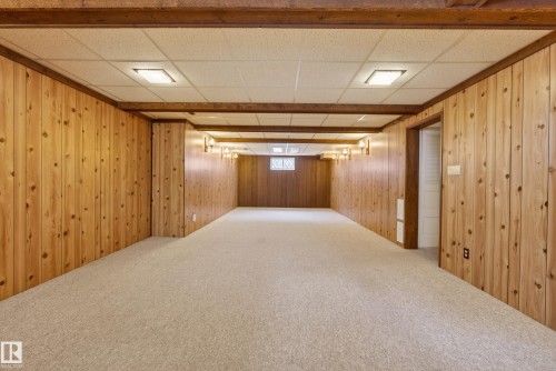 Spacious room featuring light wood paneling, light beige carpet, exposed wood beams, and recessed lighting - 12016 51 Street, Edmonton, AB - Indoor