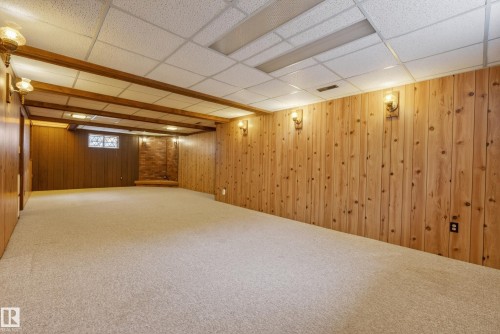 Finished room featuring light-toned carpeting, wood-paneled walls, and a drop ceiling with integrated lighting - 12016 51 Street, Edmonton, AB - Indoor