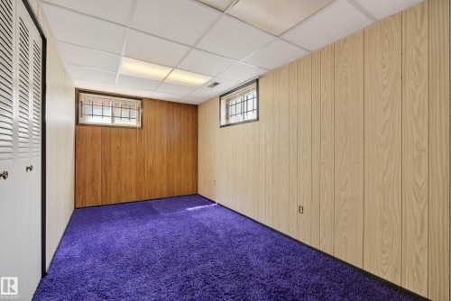 Room featuring a drop ceiling with recessed lighting, wood-paneled walls, and vibrant purple shag carpeting - 12016 51 Street, Edmonton, AB - Indoor