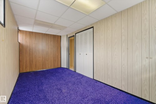 Room featuring purple carpet flooring, two-tone wood-finish wall paneling, and a drop ceiling with integrated lighting panels - 12016 51 Street, Edmonton, AB - Indoor Photo Showing Bedroom