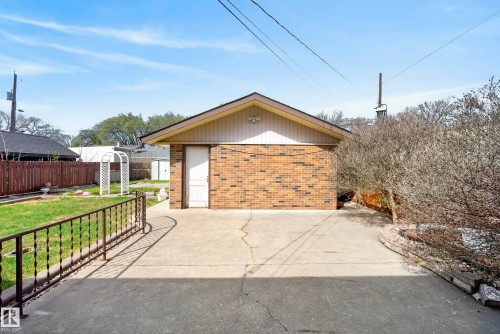 Brick structure with a side entry door, concrete driveway, and a gabled roofline - 12016 51 Street, Edmonton, AB - Outdoor
