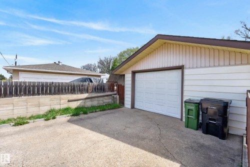 Detached garage featuring a white panel door, light-colored siding, and a brown trim - 12016 51 Street, Edmonton, AB - Outdoor With Exterior