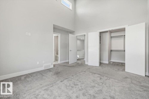 Spacious room featuring light gray carpeting, neutral wall finishes, and a high vaulted ceiling with an upper window - 9933 79 Street, Edmonton, AB - Indoor Photo Showing Other Room