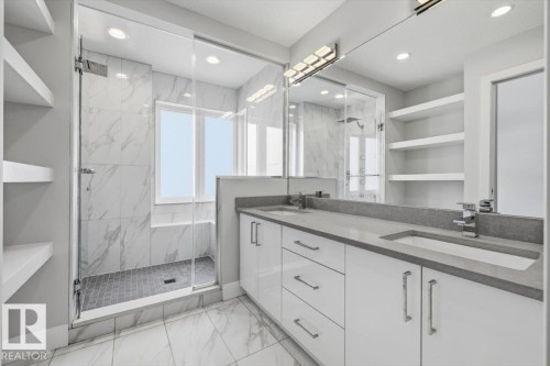 Spacious bathroom featuring a dual vanity with undermount sinks, a walk-in shower with glass enclosure, white cabinetry, and floating shelves - 9933 79 Street, Edmonton, AB - Indoor Photo Showing Bathroom