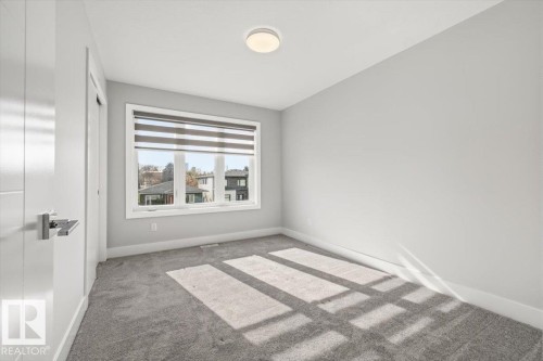 Bright room featuring light gray walls, gray carpet, and a large window with horizontal blinds - 9933 79 Street, Edmonton, AB - Indoor Photo Showing Other Room