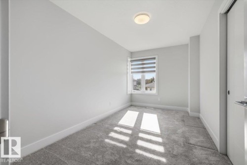 Neutral-toned room featuring a window with integrated blinds, grey carpet flooring, white baseboards, and a flush mount ceiling light fixture - 9933 79 Street, Edmonton, AB - Indoor Photo Showing Other Room