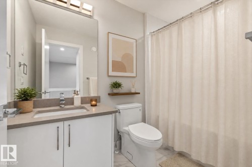 Bathroom featuring a vanity with a rectangular undermount sink, a light-colored countertop, and a large wall-mounted mirror - 9933 79 Street, Edmonton, AB - Indoor Photo Showing Bathroom