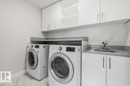 Dedicated laundry area featuring white upper and lower cabinetry, a built-in sink with a chrome faucet, light-toned countertop space, and tiled flooring - 9933 79 Street, Edmonton, AB - Indoor Photo Showing Laundry Room