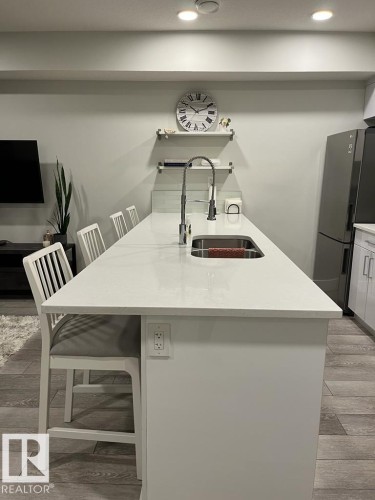 Kitchen island with an undermount sink, gooseneck faucet, and integrated seating - 9933 79 Street, Edmonton, AB - Indoor