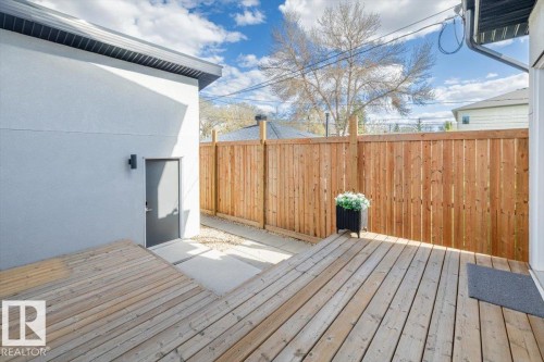 Expansive wood-finish deck with privacy fencing, a stucco exterior, and a built-in outdoor light fixture - 9933 79 Street, Edmonton, AB - Outdoor With Deck Patio Veranda With Exterior
