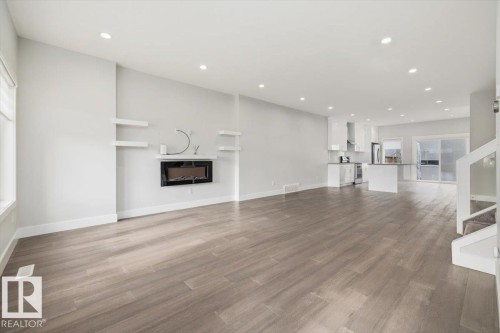 Open-concept living space featuring wood-finish flooring, recessed lighting, and a modern wall-mounted fireplace with floating shelves - 9933 79 Street, Edmonton, AB - Indoor Photo Showing Living Room With Fireplace