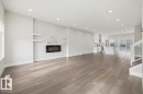 Open-concept living space featuring wood-finish flooring, recessed lighting, and a modern wall-mounted fireplace with floating shelves - 9933 79 Street, Edmonton, AB  - Indoor Photo Showing Living Room With Fireplace 
