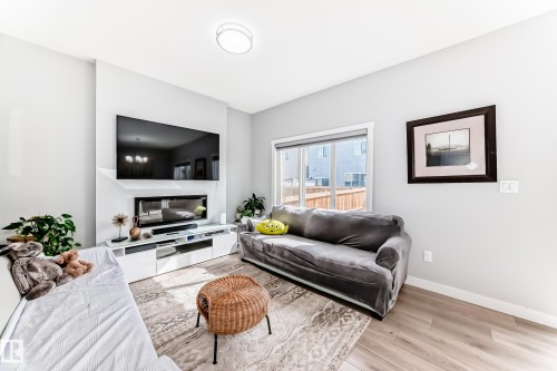 Living area featuring light-toned flooring, a fireplace, and a window providing natural light - 19635 29 Avenue, Edmonton, AB - Indoor Photo Showing Living Room With Fireplace