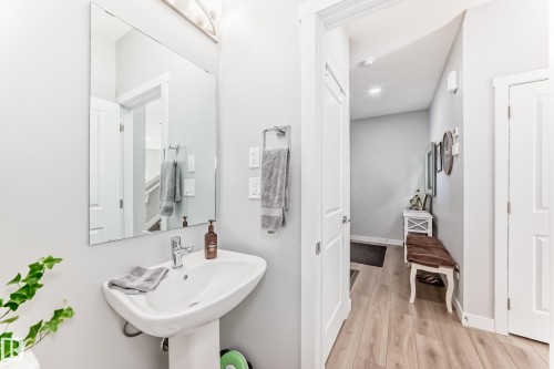 This space features a pedestal sink with a chrome faucet and a frameless wall mirror - 19635 29 Avenue, Edmonton, AB - Indoor Photo Showing Bathroom