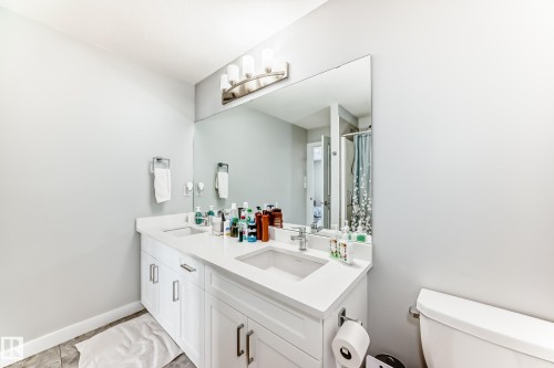 The bathroom features a double vanity with white cabinetry, light-colored countertops, and integrated sinks - 19635 29 Avenue, Edmonton, AB - Indoor Photo Showing Bathroom