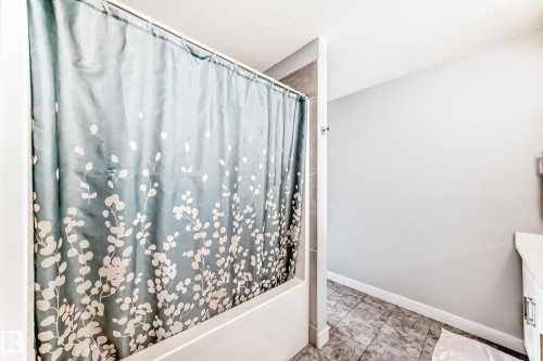 Bathroom featuring a white bathtub, a tiled shower surround, and tiled flooring - 19635 29 Avenue, Edmonton, AB - Indoor Photo Showing Bathroom