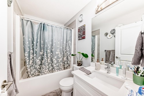 This bathroom features a bathtub with a shower, a vanity with an integrated sink, and a large mirror - 19635 29 Avenue, Edmonton, AB - Indoor Photo Showing Bathroom