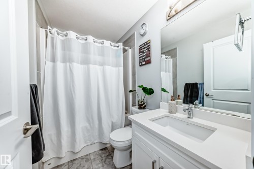 Bathroom featuring a white vanity with an integrated sink, polished chrome faucet, and a large mirror - 19635 29 Avenue, Edmonton, AB - Indoor Photo Showing Bathroom
