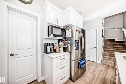 Kitchen area featuring white cabinetry, a stainless steel refrigerator, and a microwave - 19635 29 Avenue, Edmonton, AB - Indoor Photo Showing Kitchen