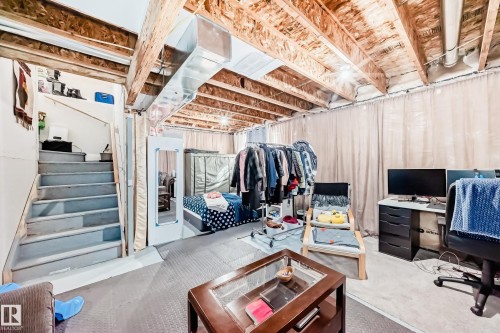 The lower level features exposed wood ceiling joists and ductwork, with neutral-toned privacy curtains along one wall - 19635 29 Avenue, Edmonton, AB - Indoor Photo Showing Basement