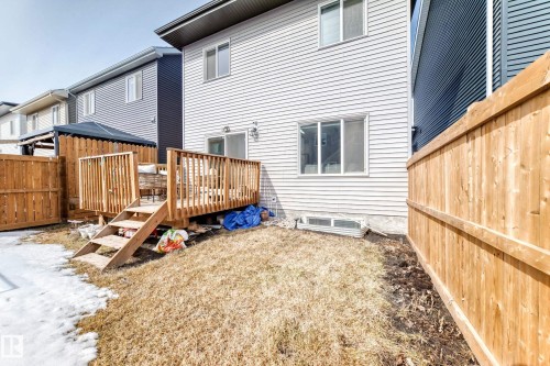 The property features light-colored horizontal siding and a wooden deck with railing and stairs - 19635 29 Avenue, Edmonton, AB - Outdoor With Exterior