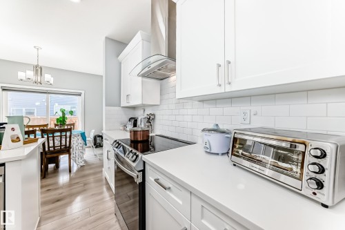 The kitchen features white cabinetry, white countertops, and a white subway tile backsplash, with a stainless steel range hood and oven - 19635 29 Avenue, Edmonton, AB - Indoor Photo Showing Kitchen With Upgraded Kitchen