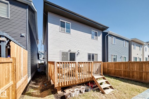 Rear exterior with light gray siding, featuring a wood deck with railing and stairs, and a sliding glass door - 19635 29 Avenue, Edmonton, AB - Outdoor With Exterior