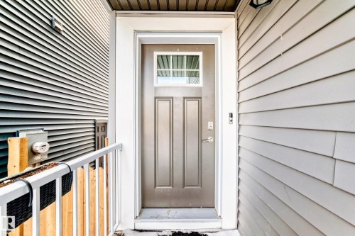 Property entrance featuring a paneled door with an upper window, a white doorframe, and light-colored siding - 19635 29 Avenue, Edmonton, AB - Outdoor With Exterior