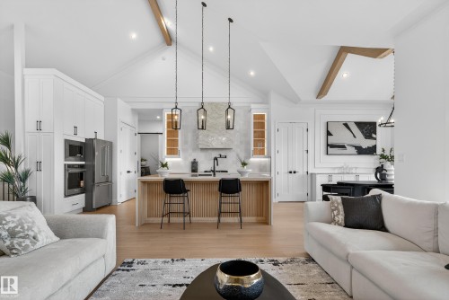 Vaulted ceiling with exposed wood beams, wood-finish flooring, and a kitchen island with pendant lighting - 711 166 Avenue, Edmonton, AB - Indoor Photo Showing Living Room