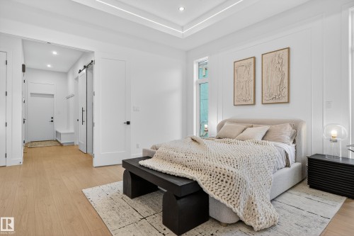 Bright sleeping area featuring light wood-finish flooring and a white tray ceiling with recessed lighting - 711 166 Avenue, Edmonton, AB - Indoor Photo Showing Bedroom