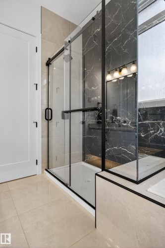 Modern bathroom featuring a glass-enclosed shower with black-framed sliding doors and a white shower pan - 711 166 Avenue, Edmonton, AB - Indoor