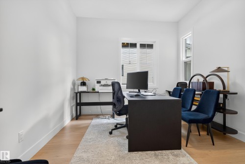 Bright room featuring light wood-finish flooring, white walls, and multiple windows - 711 166 Avenue, Edmonton, AB - Indoor Photo Showing Office