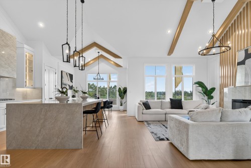 Open-concept interior featuring light wood-finish flooring and a vaulted ceiling with exposed wood beams - 711 166 Avenue, Edmonton, AB - Indoor Photo Showing Living Room