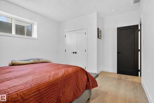 Crisp white walls define this space, featuring wood-finish flooring and a white trimmed window - 711 166 Avenue, Edmonton, AB - Indoor Photo Showing Bedroom