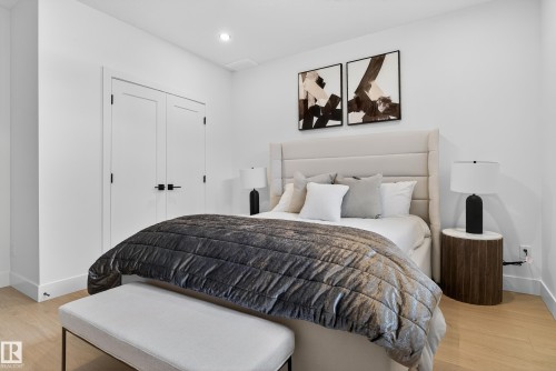 Bedroom featuring light wood-finish flooring, recessed lighting, white walls, and double closet doors with black hardware - 711 166 Avenue, Edmonton, AB - Indoor Photo Showing Bedroom