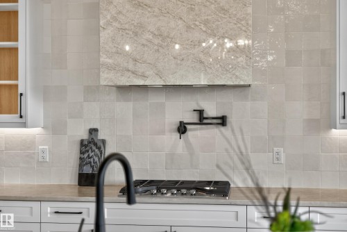 Kitchen featuring a gas range, pot filler, and custom range hood with stone-finish paneling - 711 166 Avenue, Edmonton, AB - Indoor Photo Showing Other Room