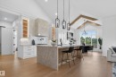 Gourmet kitchen featuring a large central island, light wood-finish flooring, white cabinetry, a custom range hood, and vaulted ceilings with exposed beams - 711 166 Avenue, Edmonton, AB  - Indoor Photo Showing Kitchen With Upgraded Kitchen 